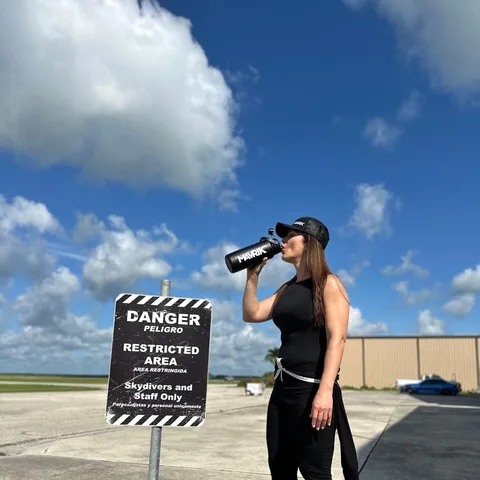 Skydiver at the drop zone drinking from a MAVRIK bottle